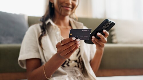 Closeup of individual with smartphone and credit card for online purchase