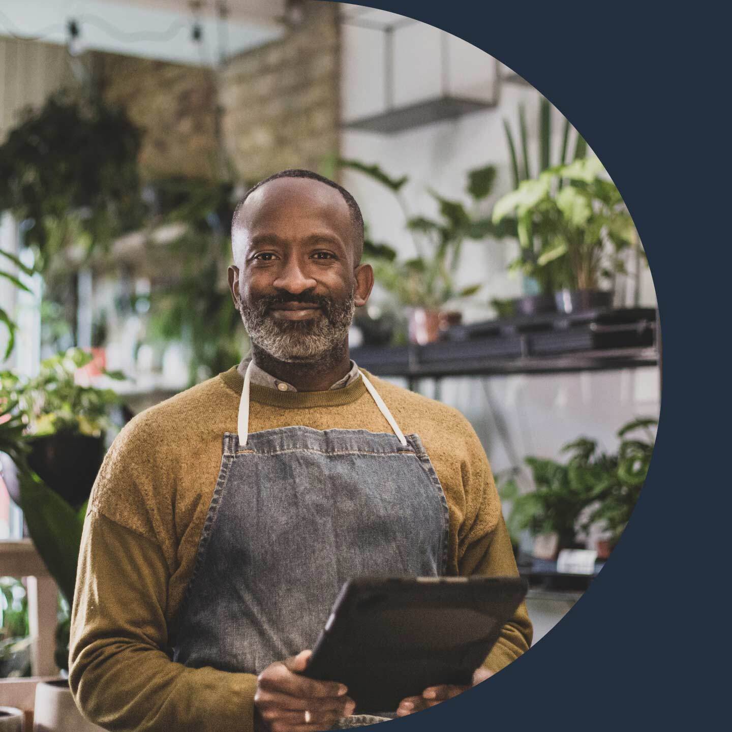 Man with apron on holding a tablet.
